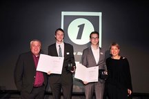 zwei Prüflinge mit Urkunden und Ausbildern