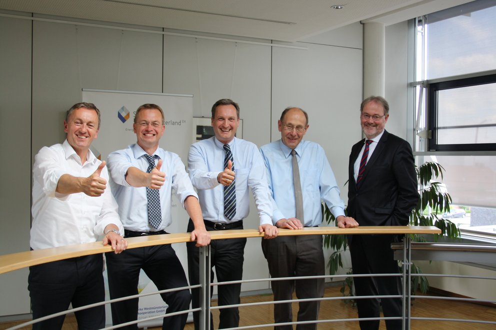 Männer in Businesskleidung. fünf Männer in Businesskleidung, die entspannt an einem Geländer stehen.