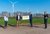 Eröffnung Windpark. vier Personen auf einem Feld mit Windrädern.
