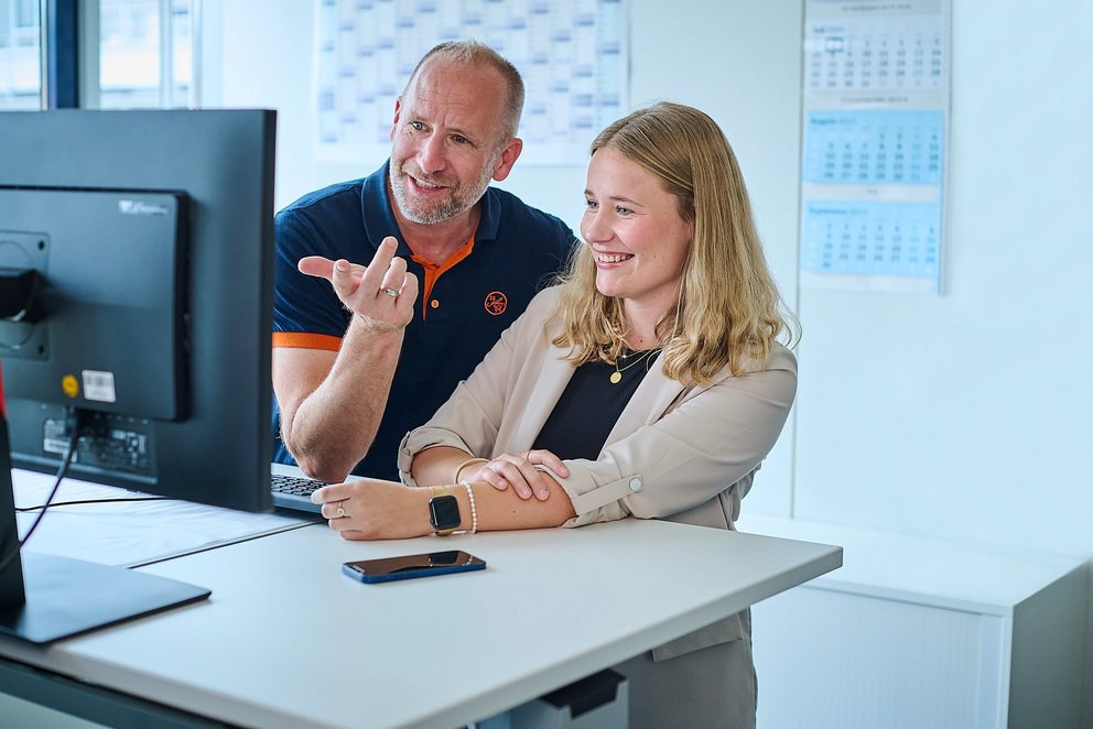 Ein Mann und eine Frau am Schreibtisch vor einem PC