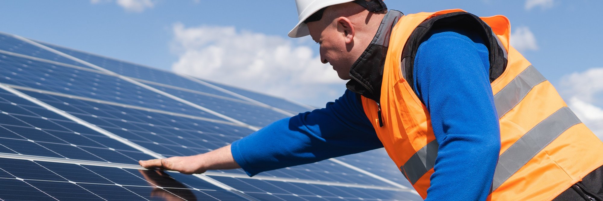 Arbeiter installiert Solarpanel in Schutzkleidung. Das Bild zeigt einen Arbeiter in Schutzkleidung und Helm, der ein Solarpanel installiert oder wartet.