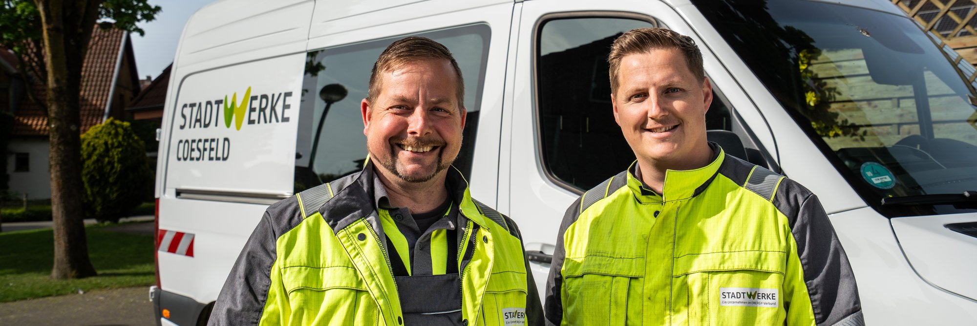 2 Mitarbeiter der Stadtwerke vor einem Fahrzeug der Stadtwerke Coesfeld.