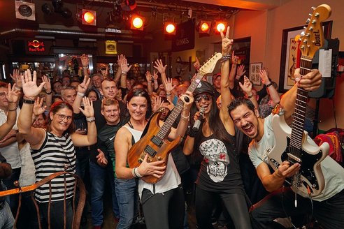 Auf dem Bild sieht man eine Gruppe von Menschen in einer Bar, die gemeinsam feiern.
