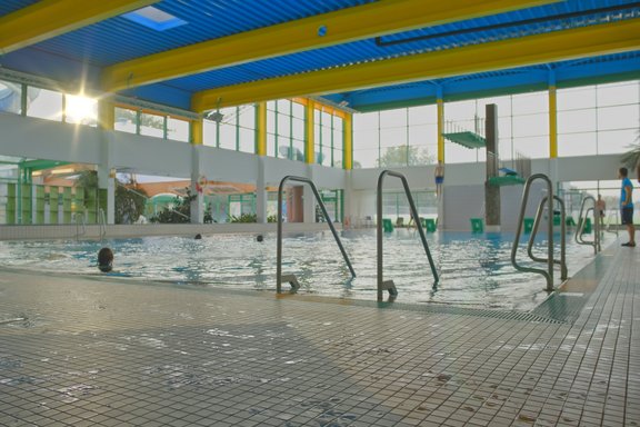 Modernes Hallenbad mit Komfort und Stil Modernes Hallenbad mit mehreren Becken, breiten Einstiegen und farbenfroher Decke.