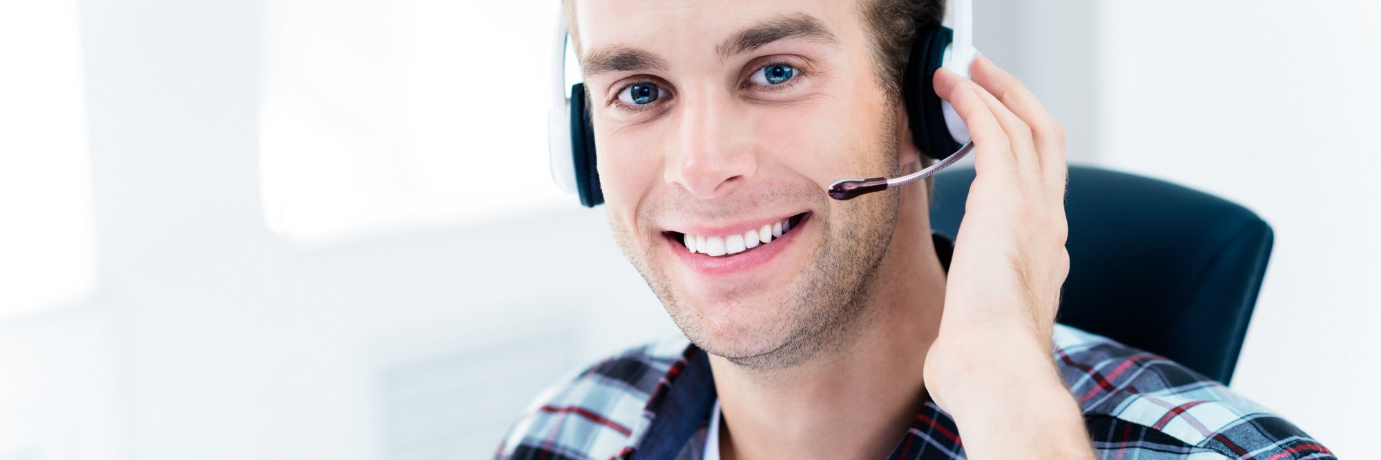 Mann arbeitet mit Headset am Computer Das Bild zeigt einen Mann, der mit einem Headset am Computer arbeitet und dabei lächelt.