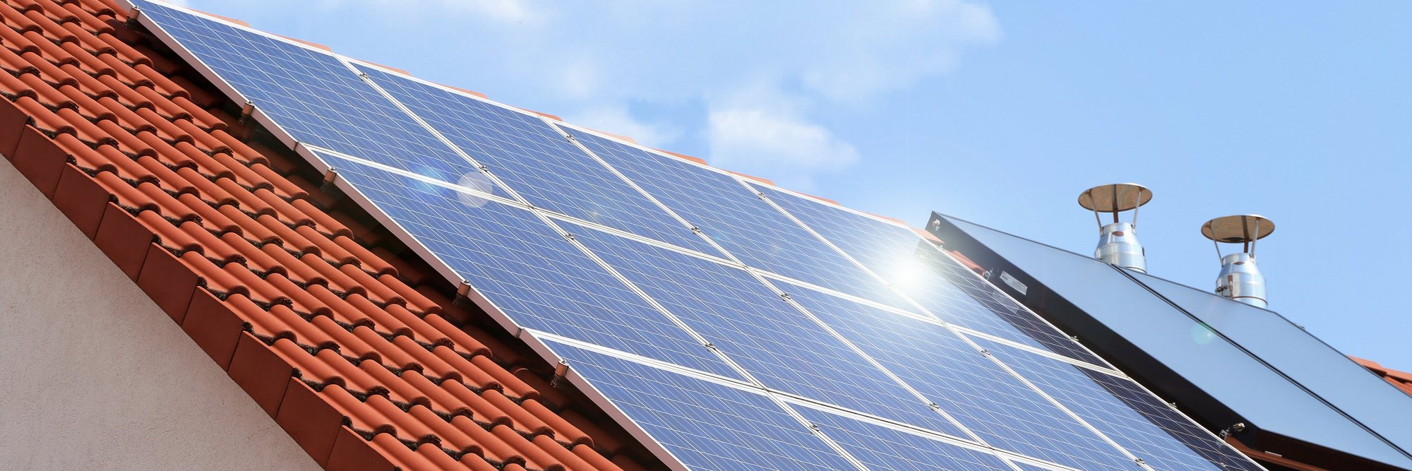 Das Bild zeigt ein Solarpanel auf einem Dach bei sonnigem Wetter.