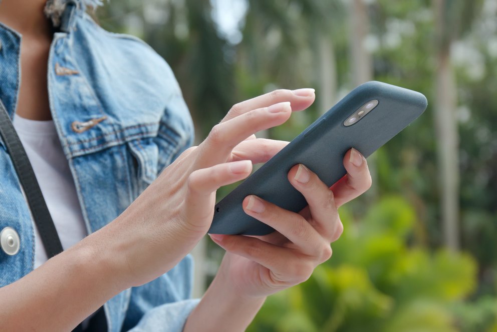 Frau mit Handy Frau mit Handy in der Hand, Wald im Hintergrund