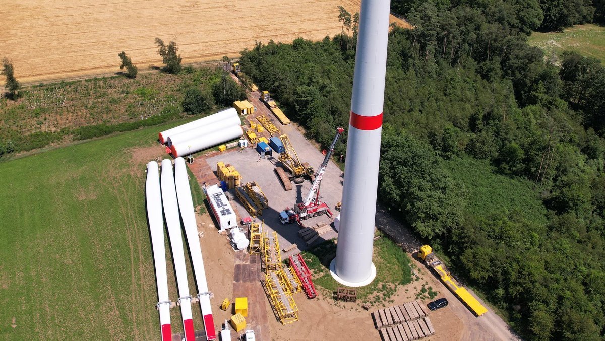 Aufbau eines Windkraftwerks, mit einer Windturbine und den Bauteilen in der Nähe, die für die Montage bereitgestellt werden.