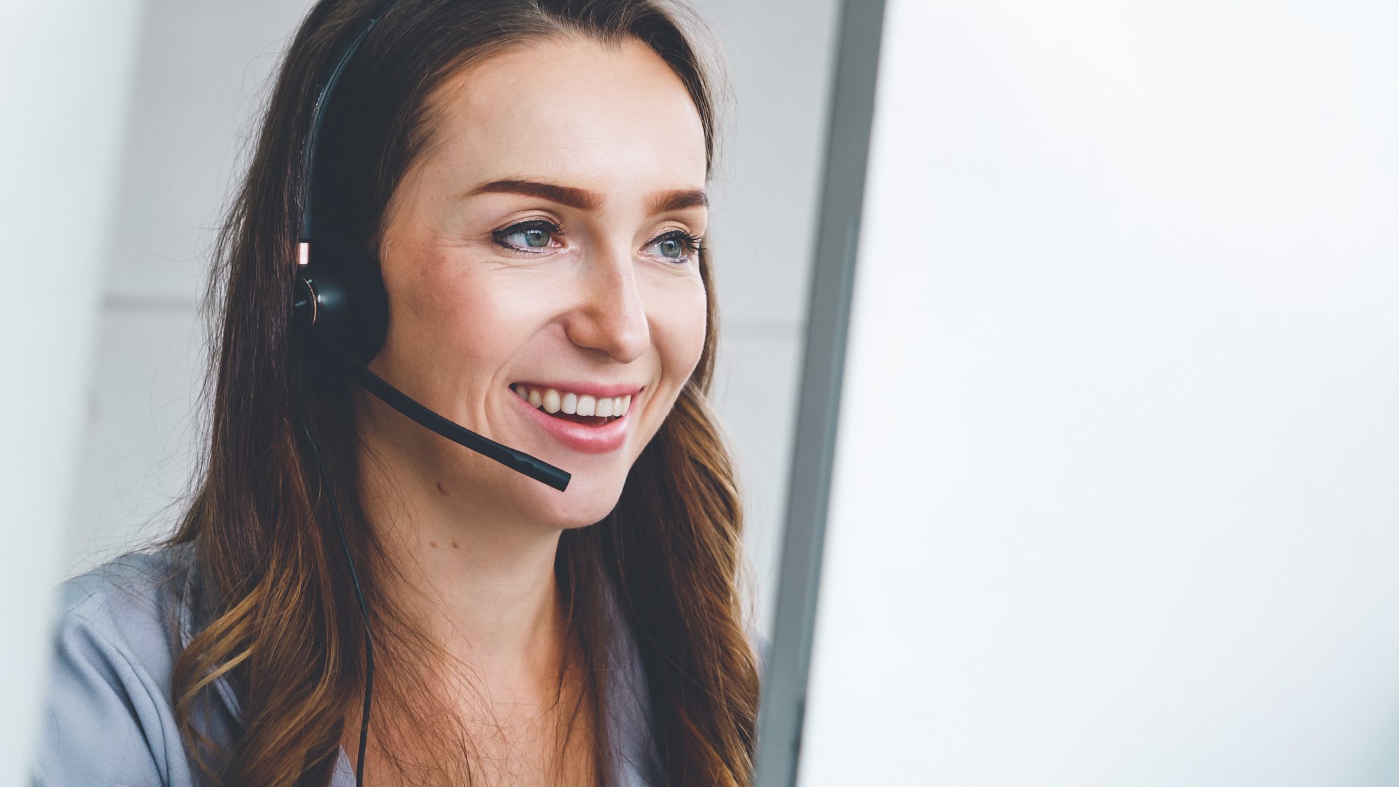 Lächelnde Person mit Headset im Gespräch Person mit einem Headset, die lächelt und wahrscheinlich in einem Kundendienstgespräch ist.