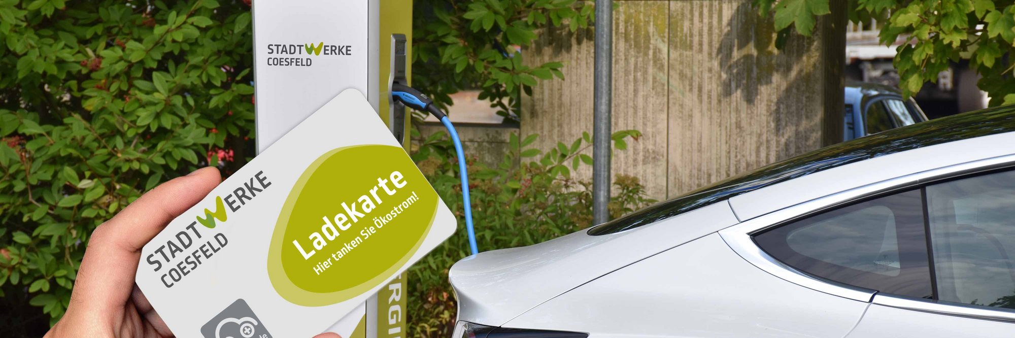 Person hält Ladekarte vor Elektroauto. Jemand hält eine Ladekarte in der Hand, während er sich einem Elektroauto nähert.