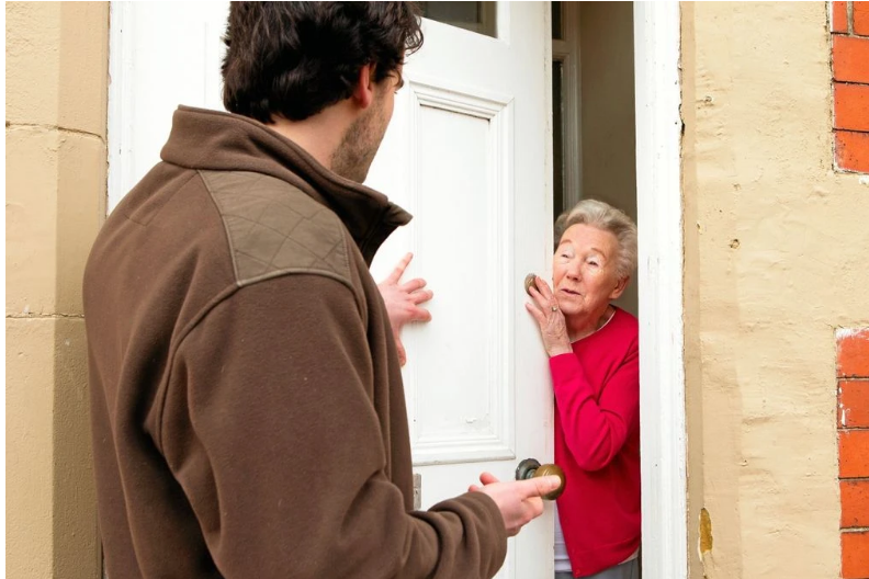 Handwerker spricht mit älterer Dame. Handwerker, der an der Tür einer älteren Dame steht und mit ihr spricht.