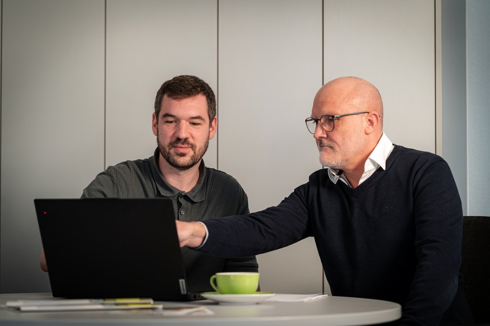 Zwei Personen schauen auf einen Laptop