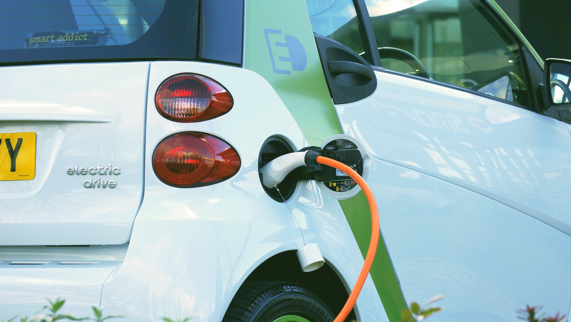 ein Elektroauto, das gerade aufgeladen wird, mit einem Ladeanschluss und einem Kabel, das an das Fahrzeug angeschlossen ist.